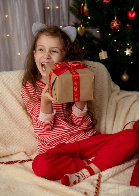 Una bella ragazza si siede sul divano con il regalo di Natale Capodanno