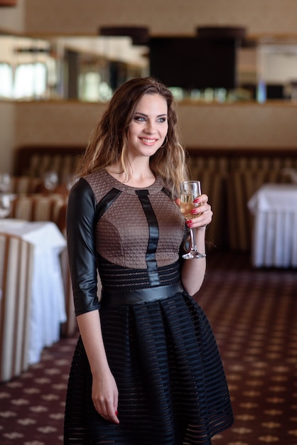 Una bella ragazza sta bevendo champagne in un ristorante.