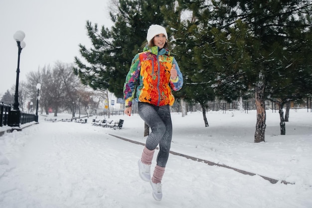 Una bella ragazza sta facendo jogging in una giornata gelida e nevosa. Sport, stile di vita sano.