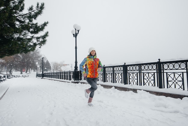 Una bella ragazza sta facendo jogging in una giornata gelida e nevosa. Sport, stile di vita sano