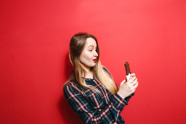 Una bella signora che ama il cioccolato su uno sfondo rosso.