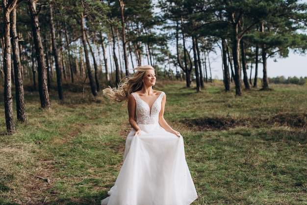 una bella sposa in abito bianco si erge sulla cima di una montagna