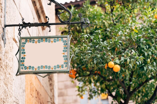 Una bella tavola vuota di forma stravagante è appesa a una cornice forgiata sulla facciata di un edificio