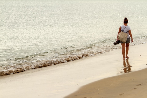 una bella turista passeggia lungo la riva di una spiaggia spagnola