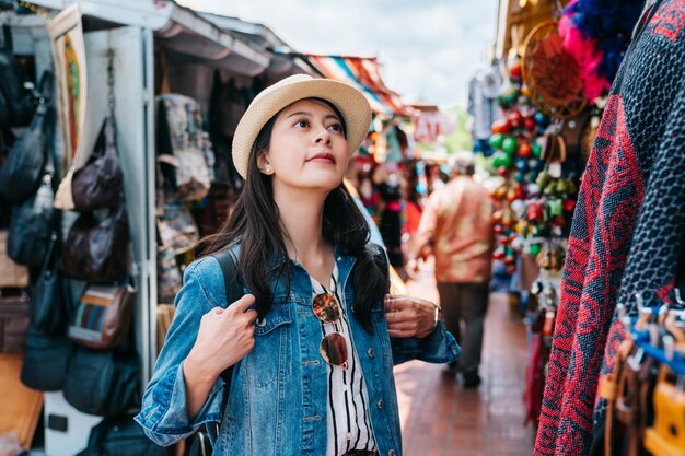 una bella viaggiatrice si fermò per strada e guardava il tessuto colorato. esperienza turistica della signora Cultura Maxican nel mercato tradizionale di Los Angeles. signora in piedi in una strada trafficata in una giornata di sole.