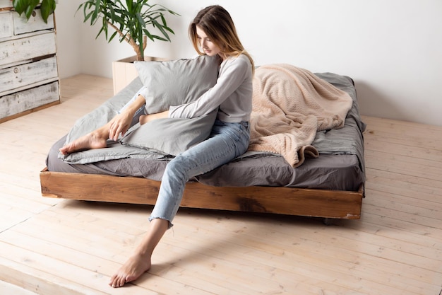 Una bellissima bionda bellissima con un viso carino è seduta sul letto