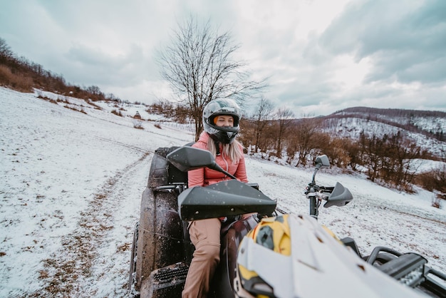 Una bellissima donna bionda si diverte nel paese delle meraviglie invernali divertendosi in un emozionante giro in quad attraverso