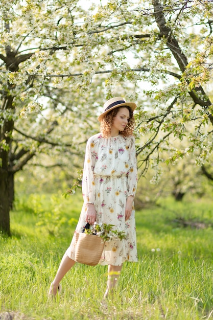 Una bellissima donna cammina in un giardino fiorito primaverile. Il concetto di unità dell'uomo con la natura.