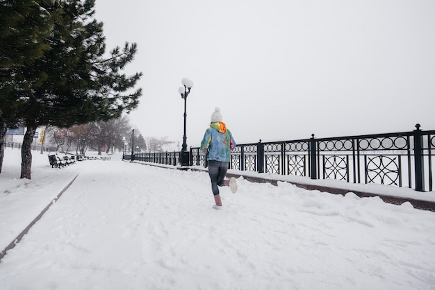 Una bellissima giovane donna fa jogging in una giornata gelida e nevosa. Sport, stile di vita sano