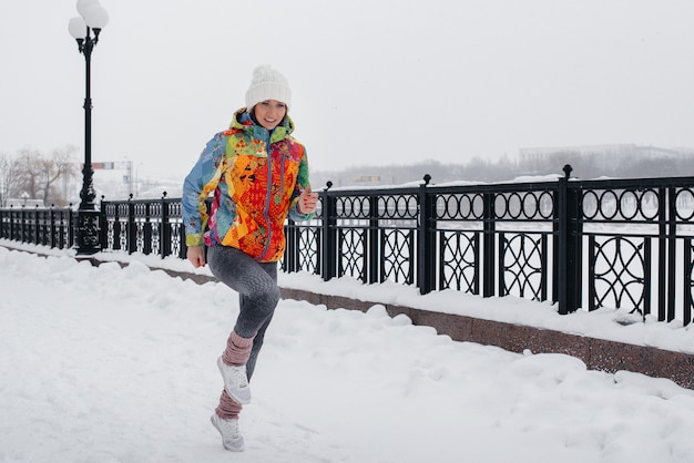 Una bellissima giovane donna fa jogging in una giornata gelida e nevosa. Sport, stile di vita sano