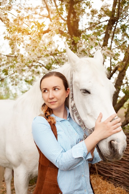 Una bellissima giovane donna posa accanto a un cavallo bianco