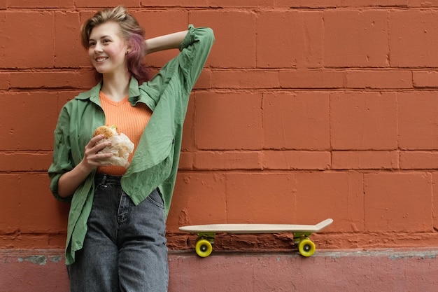 Una bellissima giovane skateboarder che mangia cibo di strada