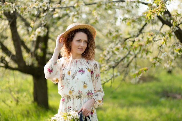 Una bellissima ragazza cammina in un giardino fiorito primaverile. Il concetto di unità dell'uomo con la natura