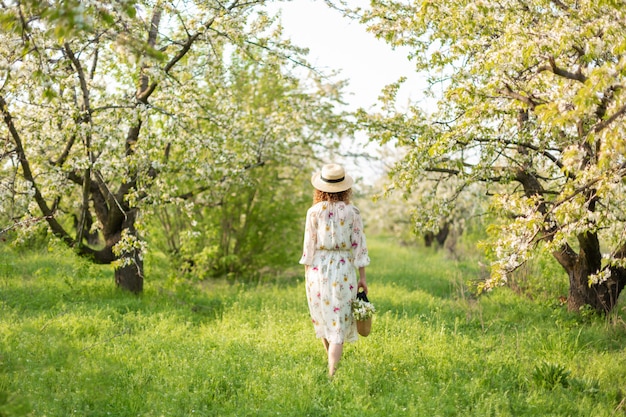 Una bellissima ragazza cammina in un giardino fiorito primaverile. Il concetto di unità dell'uomo con la natura