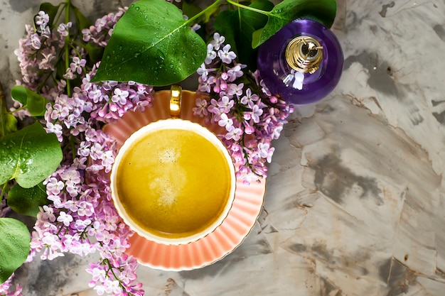 Una bellissima still life di lillà, una tazza di caffè e una bottiglia di profumo femminile