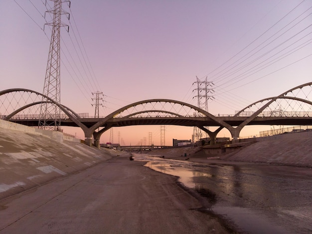 Una bellissima vista del fiume Los Angeles con il ponte della 6a strada contro il tramonto