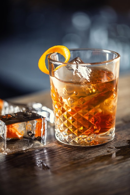 Una bevanda a rum alla vecchia moda su ghiaccio con guarnizione di scorza d'arancia