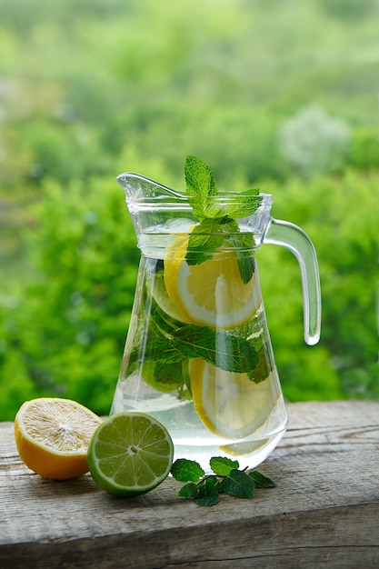 Una bevanda fredda a base di limone, lime e menta in una caraffa di vetro