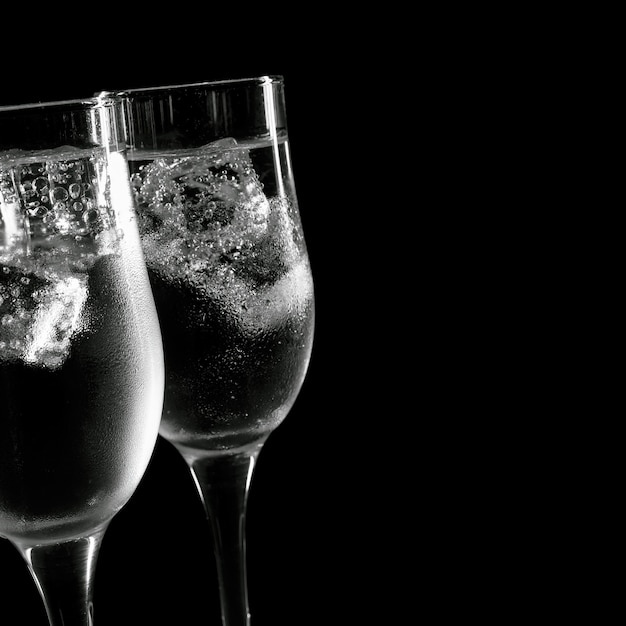 Una bevanda rinfrescante e fredda in bicchieri con ghiaccio su sfondo nero.