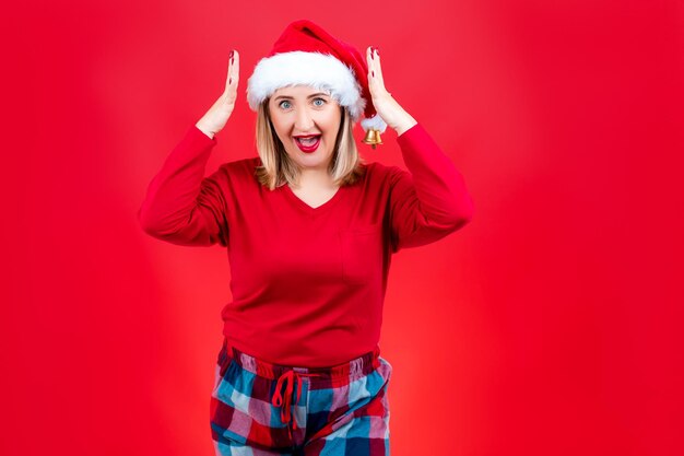 Una bionda su uno sfondo rosso o un cappello di Babbo Natale le afferra la testa e mostra emozione