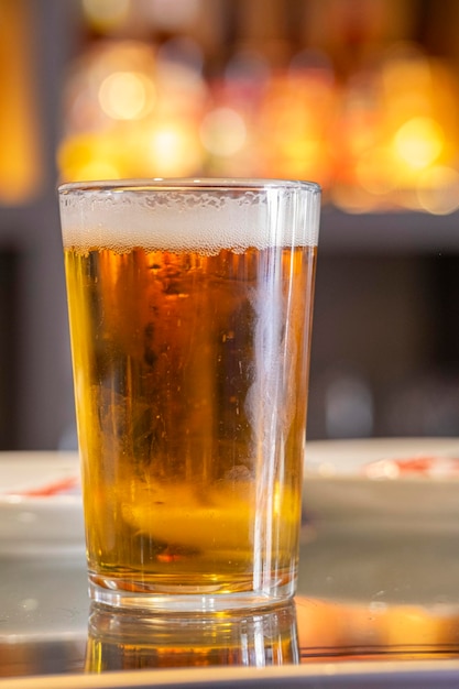 Una birra alla spina appetitosa e fresca servita in un bicchiere sul tavolo di un bar con terrazza