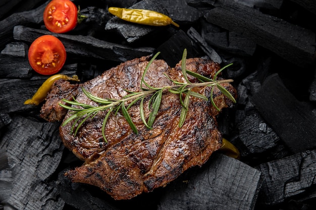 Una bistecca con un rametto di rosmarino sopra il carbone