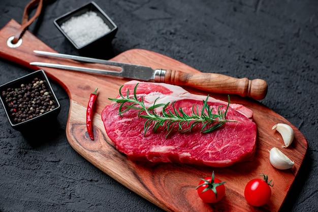 Una bistecca su un tagliere con coltello e forchetta accanto.