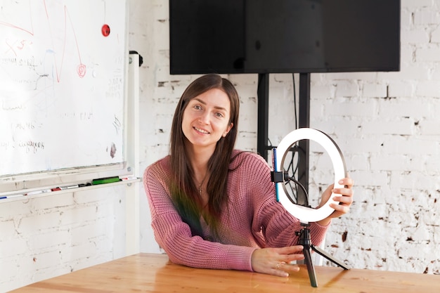 Una blogger di 25 anni conduce una trasmissione in diretta e si illumina con una lampada ad anello nella stanza luminosa