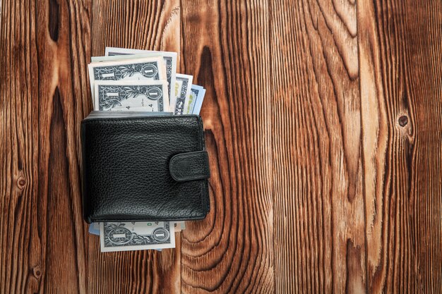 Una borsa con i dollari americani è isolata su uno sfondo di legno