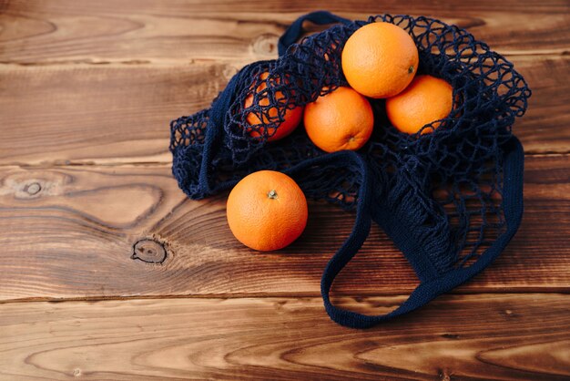 Una borsa ecologica con arance su fondo in legno
