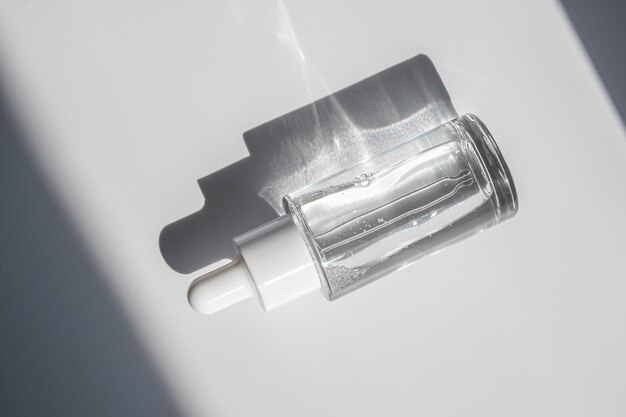 Una bottiglia bianca trasparente con siero ai raggi del sole