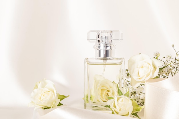 Una bottiglia chic di profumo femminile con una fragranza florale delicata su uno sfondo satinato beige fiori bianchi vista anteriore Presentazione del prodotto