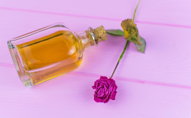 Una bottiglia con un elisir giallo su fondo di legno rosa