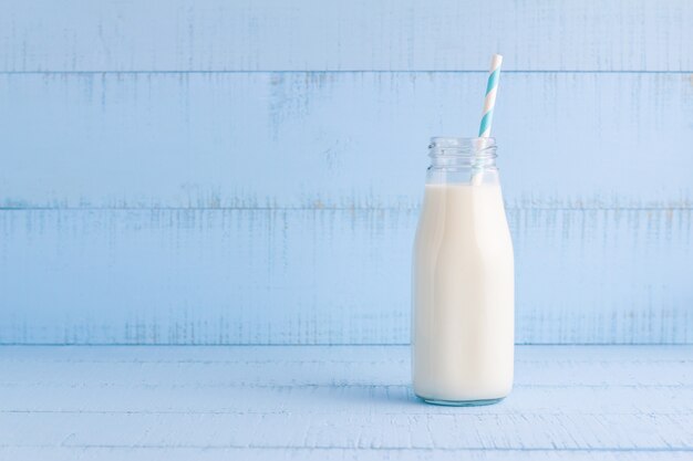 Una bottiglia di latte su fondo di legno blu.