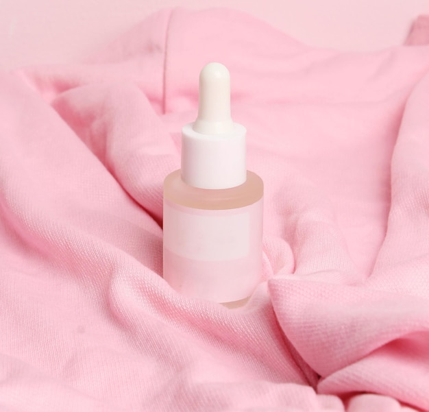 Una bottiglia di liquido con un tappo bianco si trova su una coperta rosa.