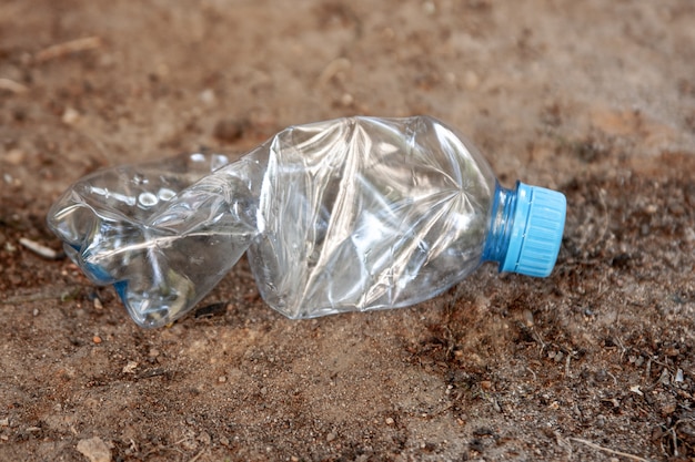 Una bottiglia di plastica giace a terra. Concetto di inquinamento ambientale.
