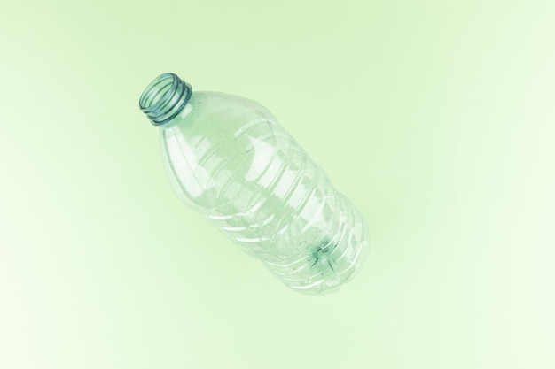 Una bottiglia di plastica vuota minimalista su uno sfondo verde chiaro pastello piatto da studio