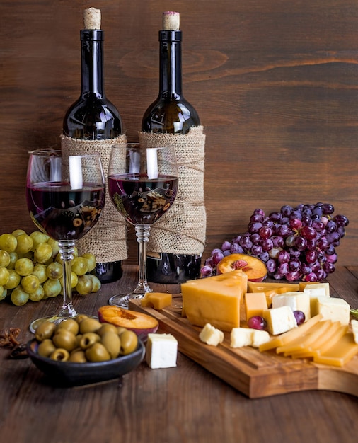 Una bottiglia di vino e formaggio su un tavolo con uva e formaggio.