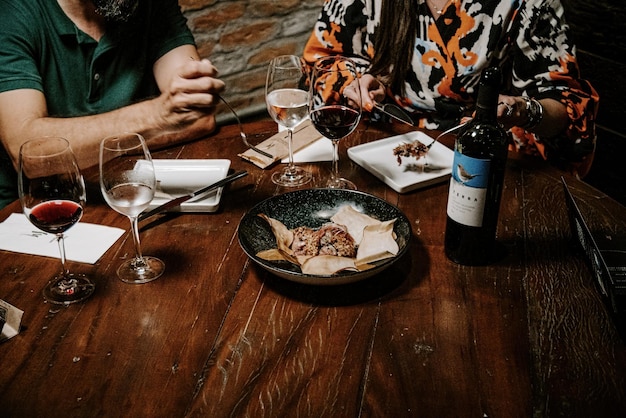 Una bottiglia di vino è sul tavolo accanto a un piatto di cibo.