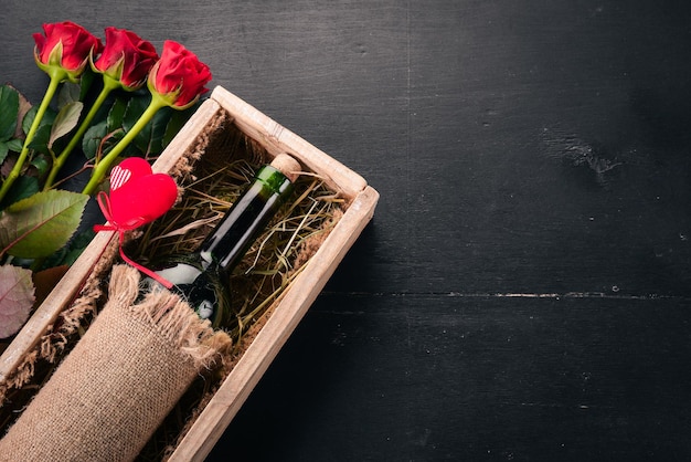 Una bottiglia di vino rosso e un bouquet di rose rosse. San Valentino. Su uno sfondo di legno. Vista dall'alto. Spazio libero per il tuo testo.