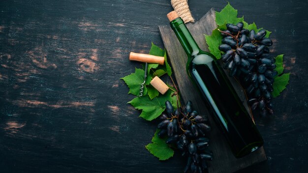 Una bottiglia di vino rosso su sfondo di legno nero Uva Spazio libero per il testo Vista dall'alto