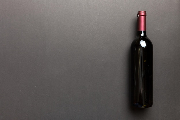 Una bottiglia di vino rosso su tavolo colorato Vista dall'alto piatto con spazio per la copia