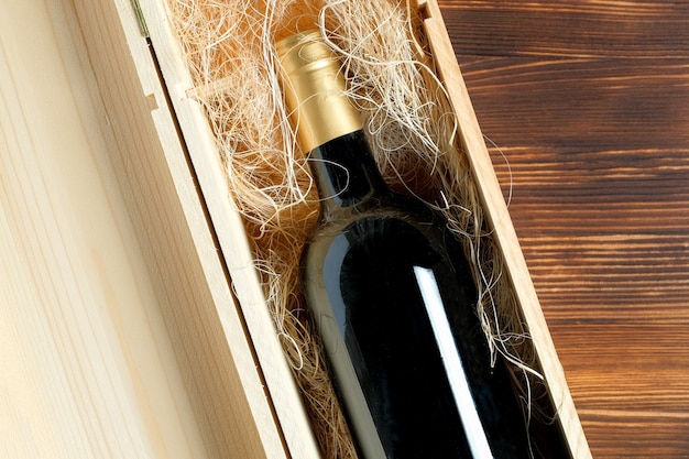 Una bottiglia di vino scura costosa in una scatola di legno su un tavolo di legno