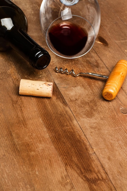 Una bottiglia e un bicchiere di vino con un vecchio cavatappi su un tavolo di legno
