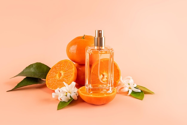 Una bottiglia trasparente di cosmetica, profumo di colonia, su una fetta di frutta matura di mandarino succosa con foglie e fiori.
