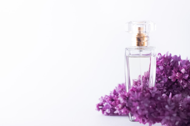 Una bottiglia trasparente di profumo in fiori lilla viola primavera fresca