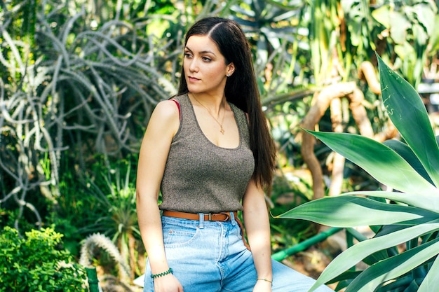 Una bruna in jeans blu a passeggiata nel giardino botanico