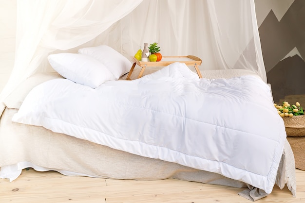 Una camera da letto accogliente in colori pastello con un pavimento in legno, un grande letto a baldacchino