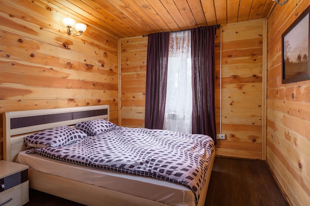 Una camera da letto con illuminazione a letto matrimoniale e una finestra con tende in una casa di legno L'interno accogliente