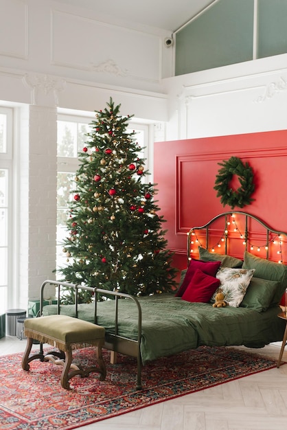 Una camera da letto decorata di Natale con un albero di Natale e una ghirlanda sul muro Un letto matrimoniale di Natale